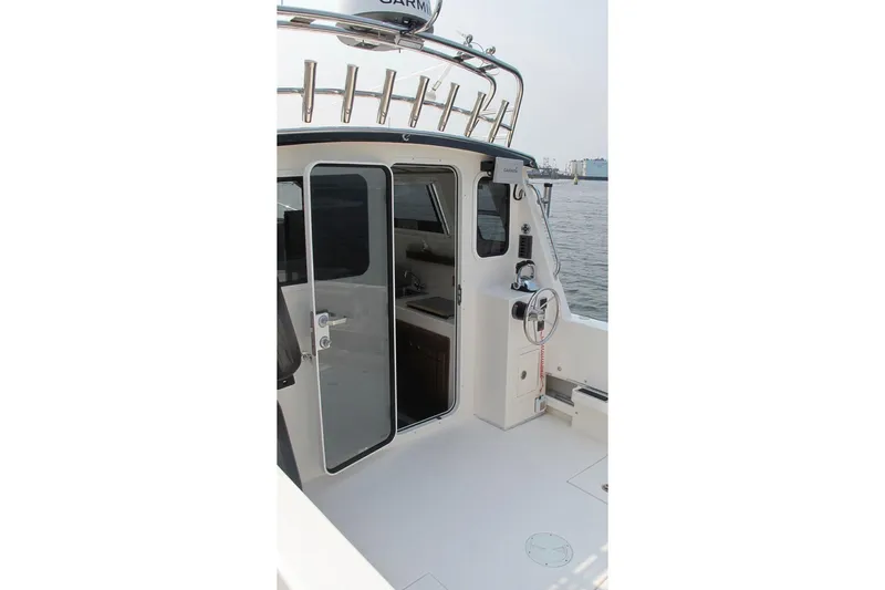 Slide: The Image of SeaSport Kodiak 2600 boat cockpit with open cabin door, featuring steering wheel and rod holders. - 4