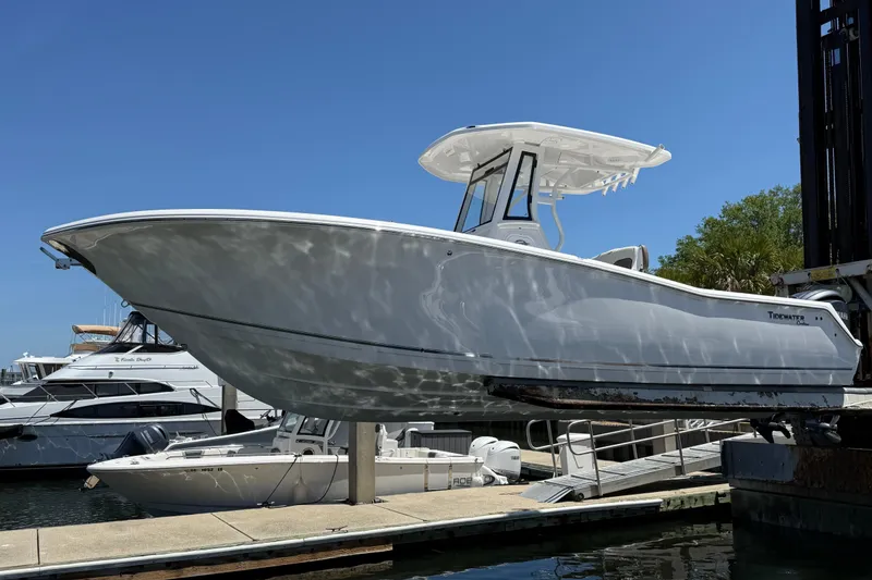 Slide: The Image of 2025 Tidewater 272 CC Adventure boat docked at marina under clear blue sky. - 2