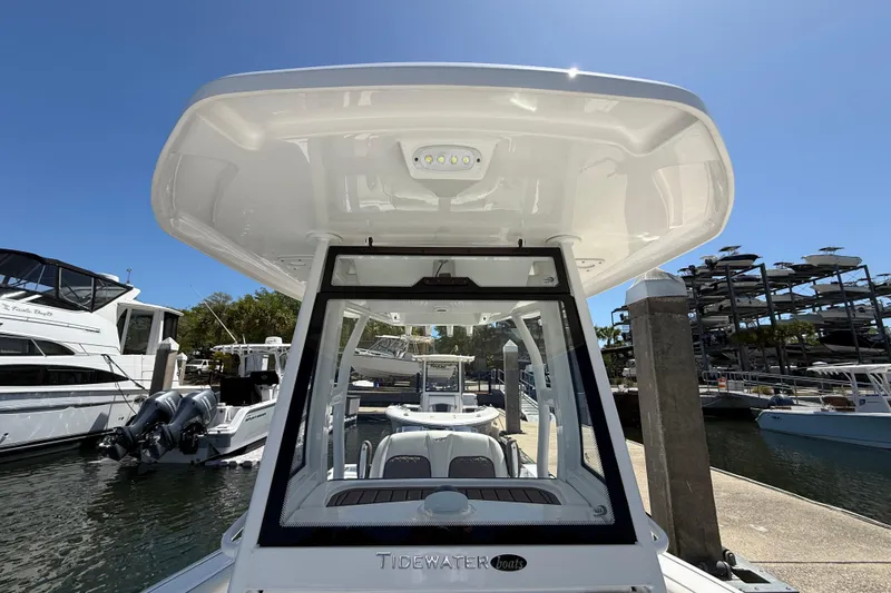 Slide: The Image of 2025 Tidewater 272 CC Adventure boat docked at marina under clear blue sky. - 22
