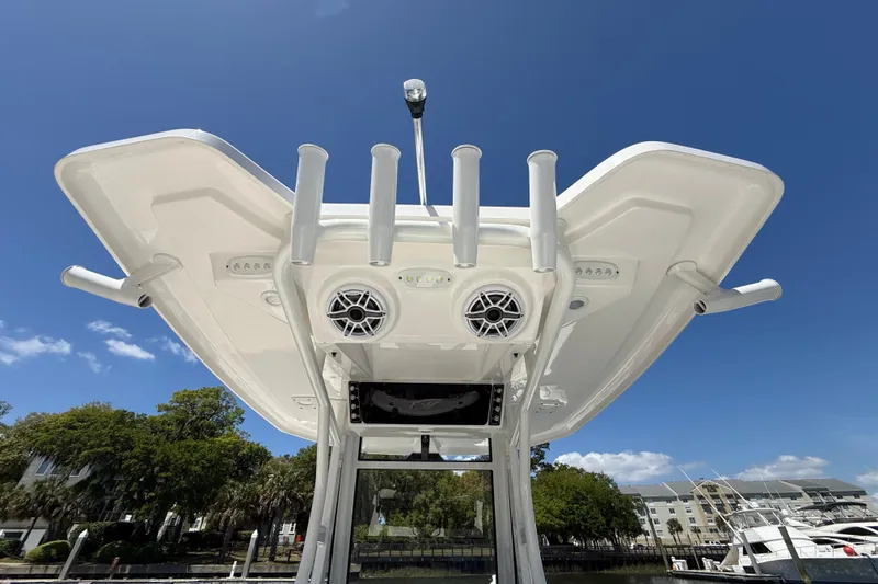 Slide: The Image of 2025 Tidewater 272 CC Adventure boat with rod holders and speakers, under clear blue sky. - 23
