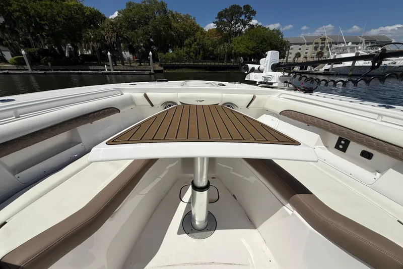 Slide: The Image of 2025 Tidewater 272 CC Adventure boat interior with table and seating, docked by water. - 33
