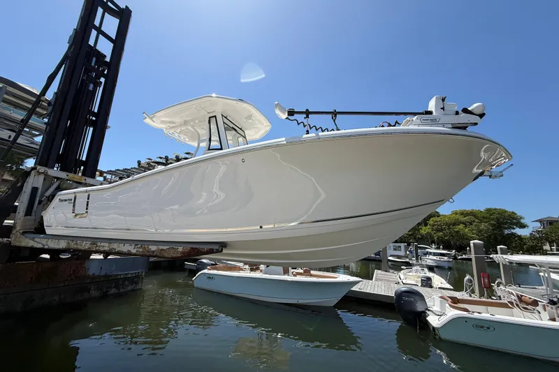 Slide: The Image of 2025 Tidewater 272 CC Adventure boat lifted at marina under clear blue sky. - 4