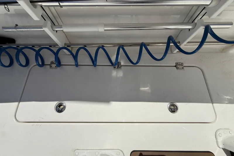 Slide: The Image of 2025 Tidewater 272 CC Adventure boat deck with blue coiled hose and storage hatch. - 40
