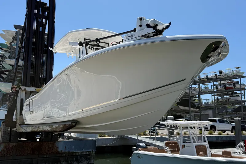 Slide: The Image of 2025 Tidewater 272 CC Adventure boat on lift at marina, clear sky background. - 5