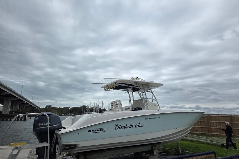 The Image of 2004 Boston Whaler 320 Outrage boat docked under cloudy skies near a bridge. - 0