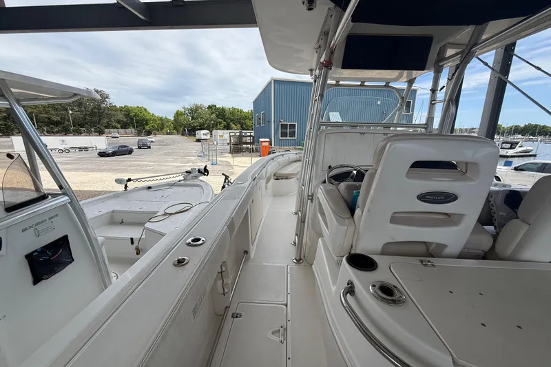 Slide: The Image of 2004 Boston Whaler 320 Outrage boat interior, showcasing seating and helm area at a marina. - 12