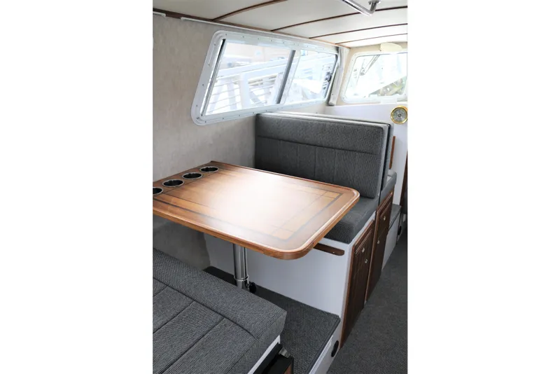 Slide: The Image of Interior of 2026 SeaSport Aleutian 2600 boat with wooden table and cushioned seating. - 23