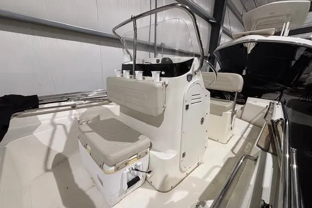Slide: The Image of 2018 Boston Whaler 150 Montauk boat interior with seating and console in a storage facility. - 5