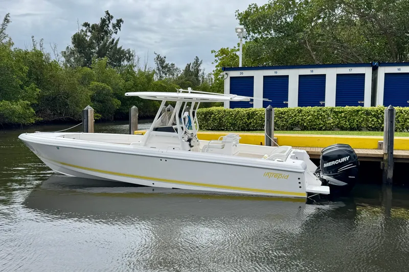 The Image of 2013 Intrepid 300 Center Console boat docked near storage units. - 1