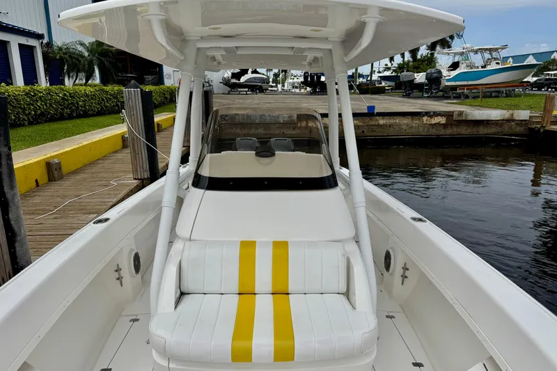 Slide: The Image of 2013 Intrepid 300 Center Console boat docked, featuring white and yellow seating. - 15