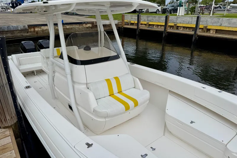 Slide: The Image of 2013 Intrepid 300 Center Console boat docked, featuring white and yellow seating. - 20