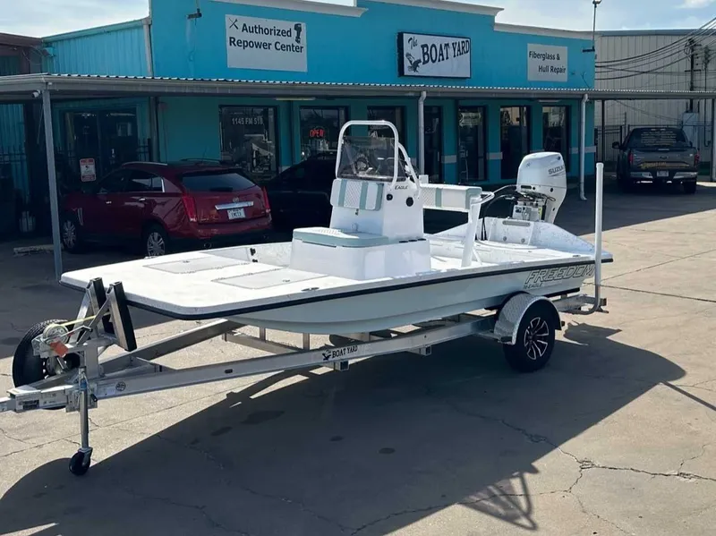 The Image of 2026 Freedom EAGLE boat on trailer outside repair shop. - 1