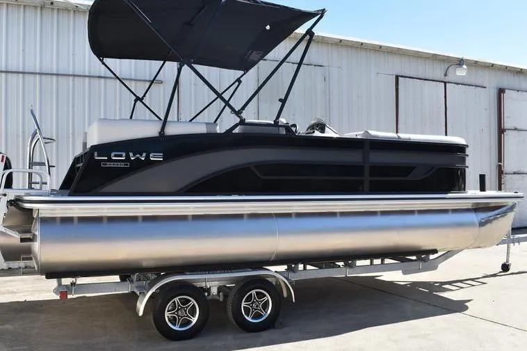 Slide: The Image of 2026 Lowe SS 230 pontoon boat on trailer, black canopy, parked outdoors. - 8