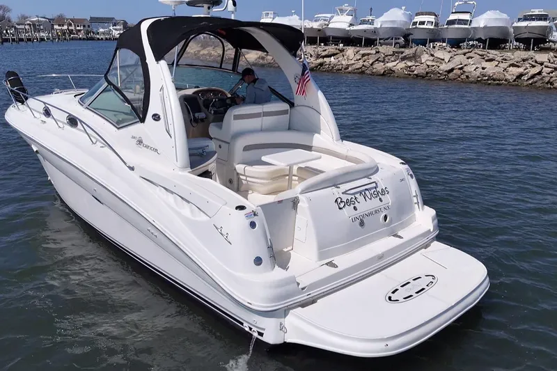 Slide: The Image of 2003 Sea Ray Sundancer 320 yacht cruising near a marina with docked boats. - 2