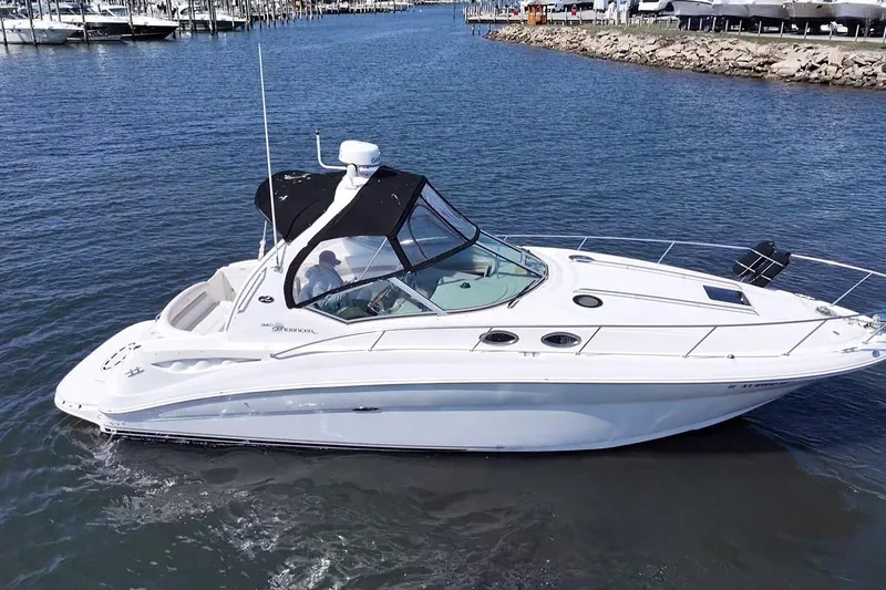 Slide: The Image of 2003 Sea Ray Sundancer 320 cruising on calm waters near a marina. - 6