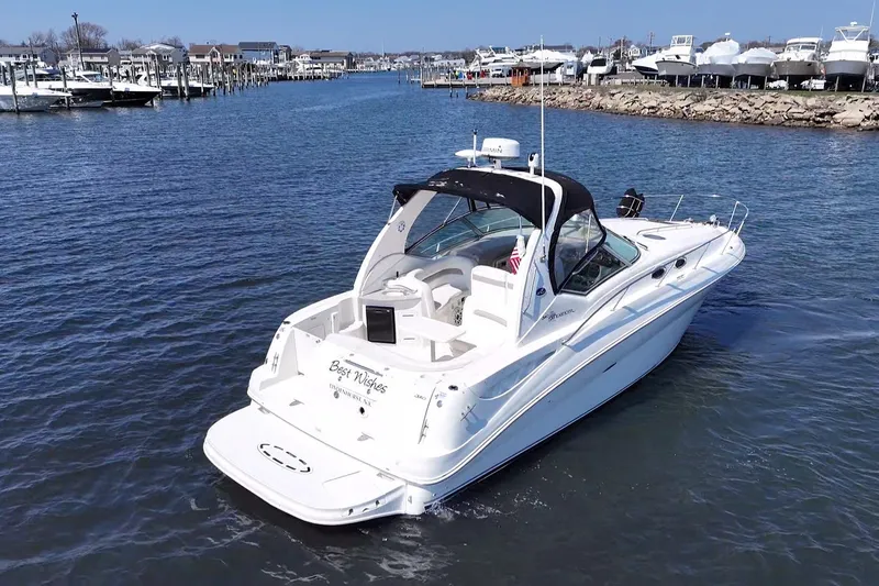 Slide: The Image of 2003 Sea Ray Sundancer 320 cruising in a marina, showcasing sleek design and luxury features. - 7