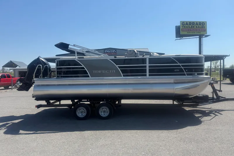 The Image of 2026 Trifecta 22 LE RF LE 2.75 pontoon boat on trailer, parked outdoors. - 1