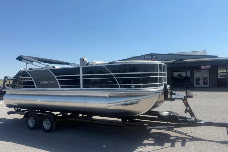 Slide: The Image of 2026 Trifecta 22 LE RF LE 2.75 pontoon boat on trailer, parked outside dealership. - 3
