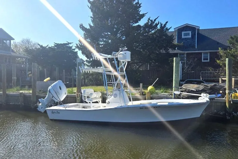 Slide: The Image of 2023 Layton Bay 22 boat docked by a waterfront home under clear blue skies. - 5