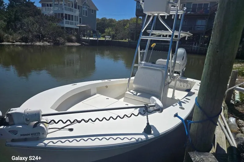 Slide: The Image of 2023 Layton Bay 22 boat docked by waterfront homes, featuring Minn Kota trolling motor. - 7
