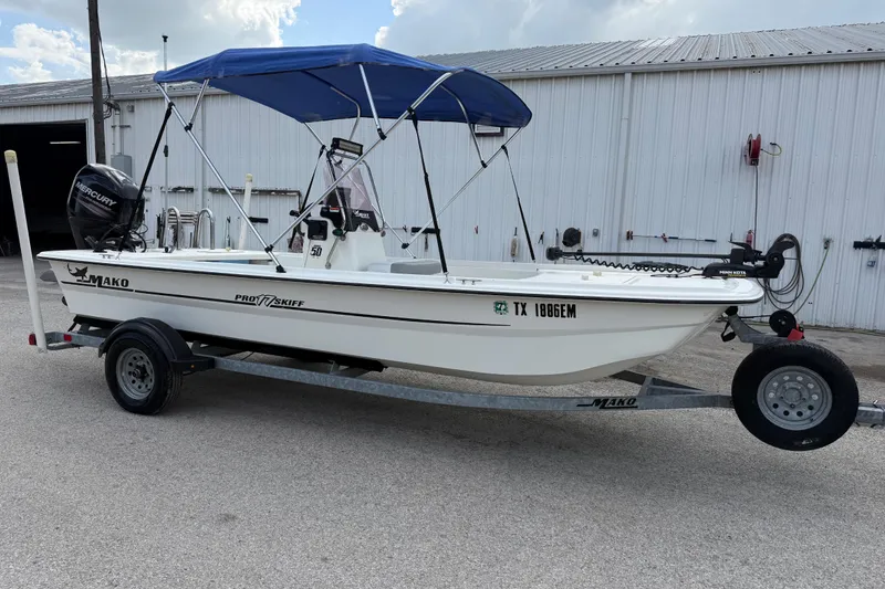 Slide: The Image of 2018 Mako Pro Skiff 17 CC boat on trailer with blue canopy and Mercury engine. - 15
