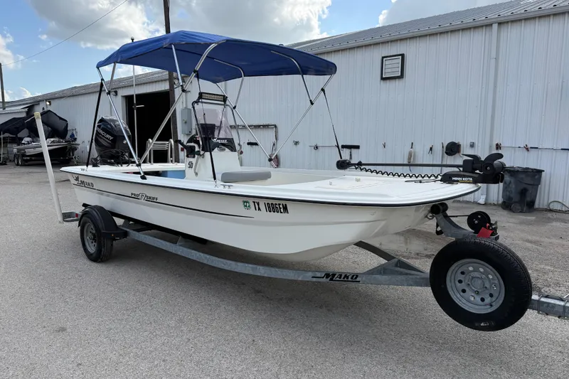 Slide: The Image of 2018 Mako Pro Skiff 17 CC boat with blue canopy on trailer. - 16