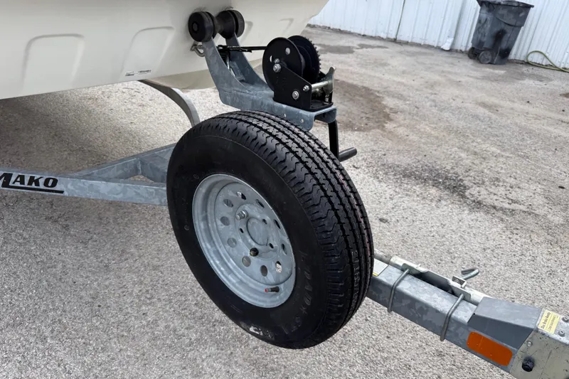 Slide: The Image of Trailer wheel of a 2018 Mako Pro Skiff 17 CC boat on pavement. - 18