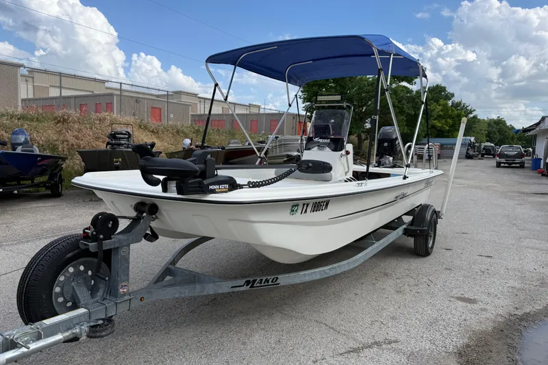 The Image of 2018 Mako Pro Skiff 17 CC boat on trailer with blue canopy, parked outdoors. - 2