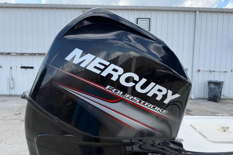 Slide: The Image of Mercury FourStroke engine on 2018 Mako Pro Skiff 17 CC boat, parked near a white building. - 33