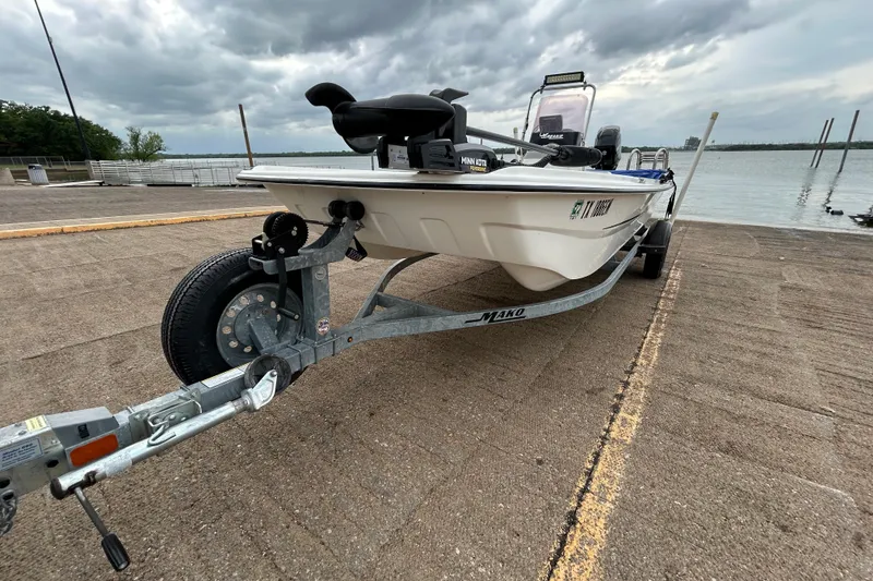 Slide: The Image of 2018 Mako Pro Skiff 17 CC on trailer by a lake under cloudy skies. - 43