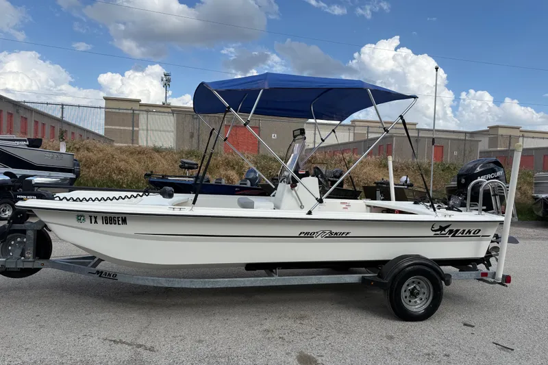 Slide: The Image of 2018 Mako Pro Skiff 17 CC boat on trailer with blue canopy, parked outdoors. - 5