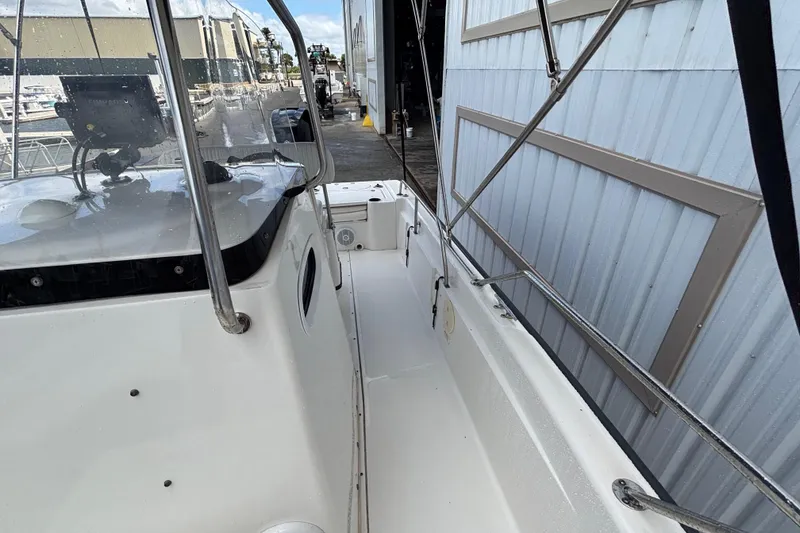 Slide: The Image of 2005 Boston Whaler 220 Dauntless boat docked, showcasing side deck and railing. - 11