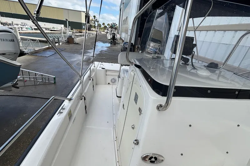 Slide: The Image of 2005 Boston Whaler 220 Dauntless boat docked at marina, showcasing sleek design and spacious deck. - 12