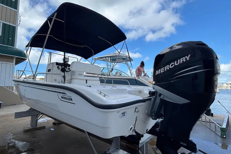 Slide: The Image of 2005 Boston Whaler 220 Dauntless boat with Mercury engine, docked under blue sky. - 5