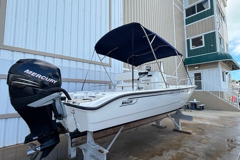 Slide: The Image of 2005 Boston Whaler 220 Dauntless boat with Mercury engine, docked near a building. - 6