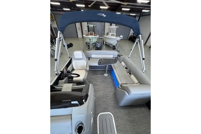 Slide: The Image of 2021 Bennington L 23 Swingback pontoon boat interior with seating and canopy in showroom. - 23