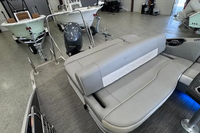 Slide: The Image of 2021 Bennington L 23 Swingback pontoon boat interior with gray seating and motor in showroom. - 24