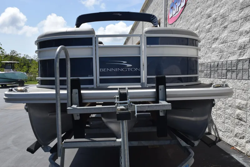 Slide: The Image of 2021 Bennington L 23 Swingback pontoon boat on trailer, parked outdoors. - 3