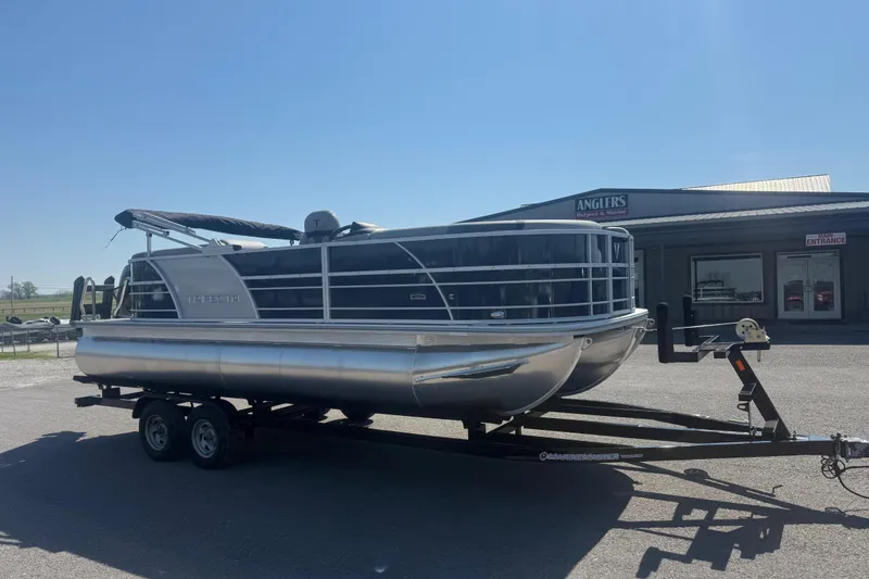 Slide: The Image of 2026 Trifecta 22RFCS3 pontoon boat on trailer, parked outside Anglers store. - 3