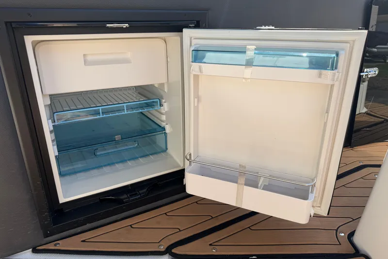 Slide: The Image of Open refrigerator on 2019 Rinker EX 320 boat, showcasing interior storage compartments. - 16