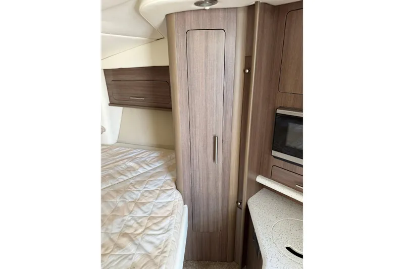 Slide: The Image of 2019 Rinker EX 320 interior with beige leather seating and wooden cabinetry. - 41