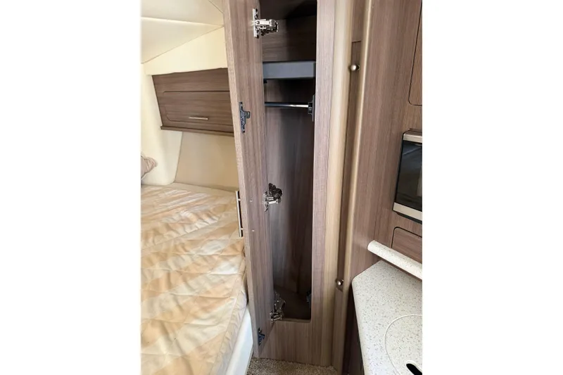 Slide: The Image of 2019 Rinker EX 320 cabin interior with wood cabinetry and bed. - 42