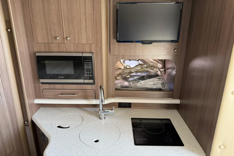 Slide: The Image of 2019 Rinker EX 320 boat interior kitchen with microwave, TV, and modern appliances. - 44