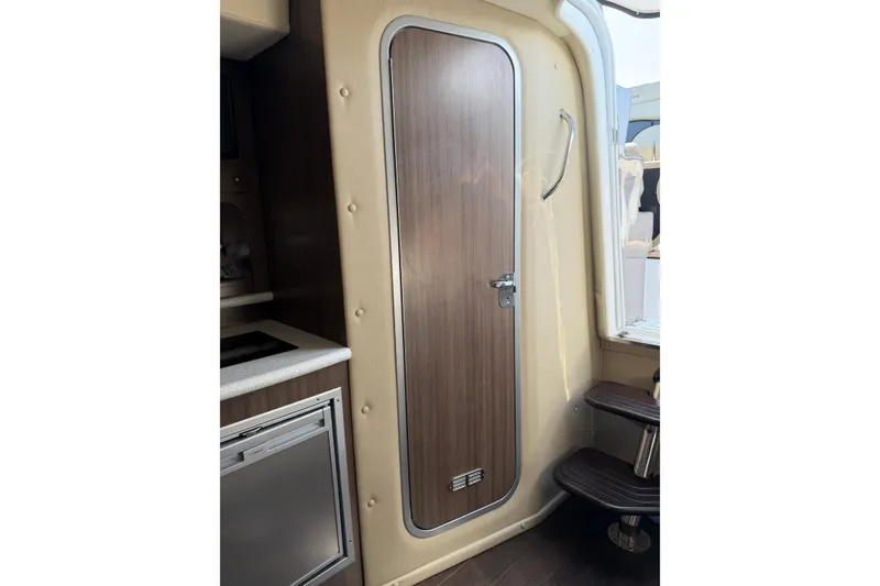Slide: The Image of 2019 Rinker EX 320 interior with Dometic fridge and wood cabinetry. - 47