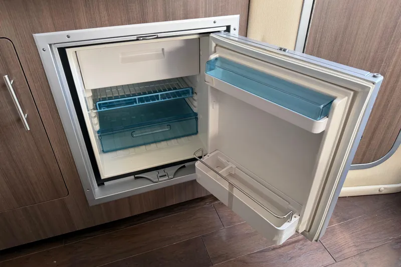 Slide: The Image of Open refrigerator in 2019 Rinker EX 320 boat, showcasing interior storage compartments. - 48