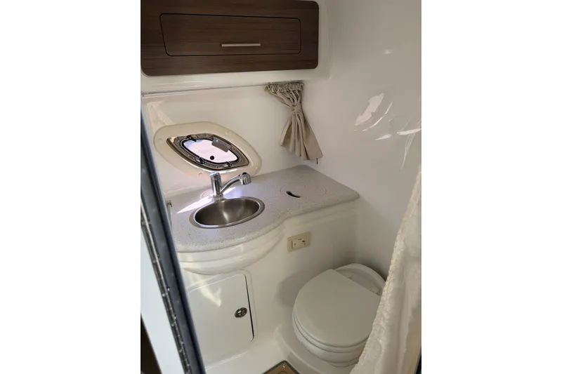 Slide: The Image of 2019 Rinker EX 320 boat bathroom with sink, toilet, and porthole window. - 50