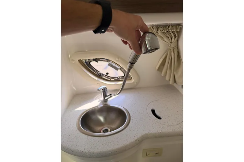 Slide: The Image of 2019 Rinker EX 320 boat interior sink with pull-out faucet and porthole window. - 51