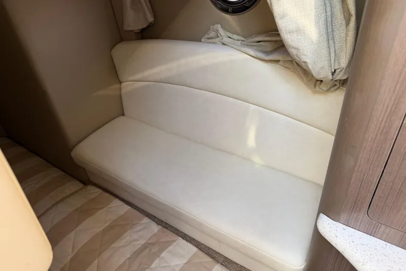 Slide: The Image of 2019 Rinker EX 320 cabin interior with beige seating and curtains. - 55