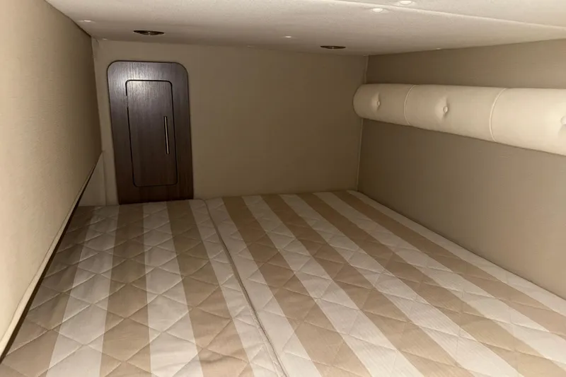 Slide: The Image of 2019 Rinker EX 320 cabin interior with beige mattress and wooden door. - 57