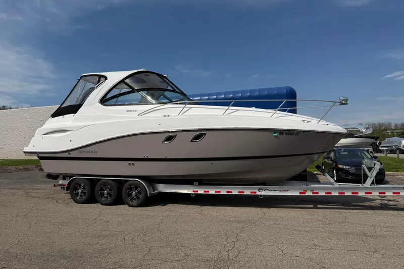 Slide: The Image of 2019 Rinker EX 320 boat on trailer, parked outdoors under clear sky. - 68